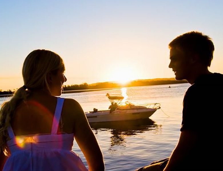 Couple sitting on the riverfront in front of boat