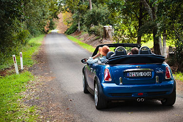 Couple driving along a green country road in convertible
