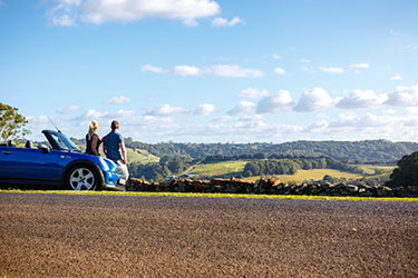 Couple leaning on car overlooking rural vista
