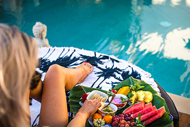 Lady sitting by pool with fruit platter