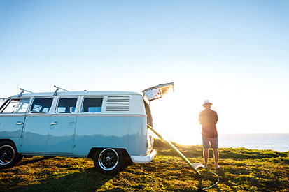 Man looking at beach with surfboard in Kombi