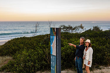 Couple reading sign with dusk sunset in background