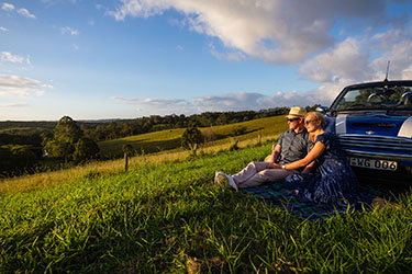 Couple cuddling watching the sun set over the countryside