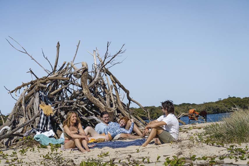 Island Life 3 - Couples lying on sand with stick tent in background