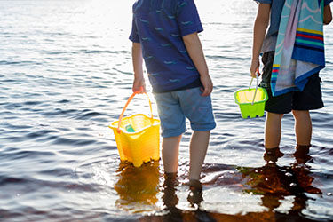 Kids holding buckets walking through Lake Ainsworth