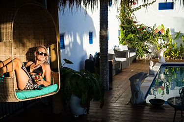 Lady sitting in big chair by pool with sun rays on her