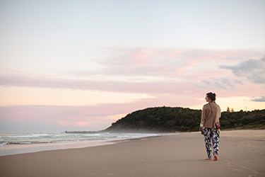 Lady walking along beach at dusk