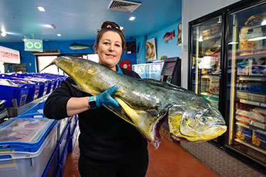 Lady at fish co-op holding large fish
