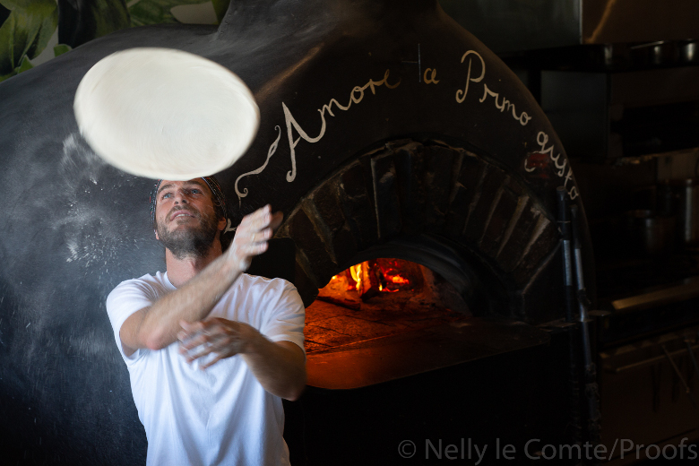 Quattro Beachfront Italian Lennox Head - Chef tossing pizza doe with pizza oven behind