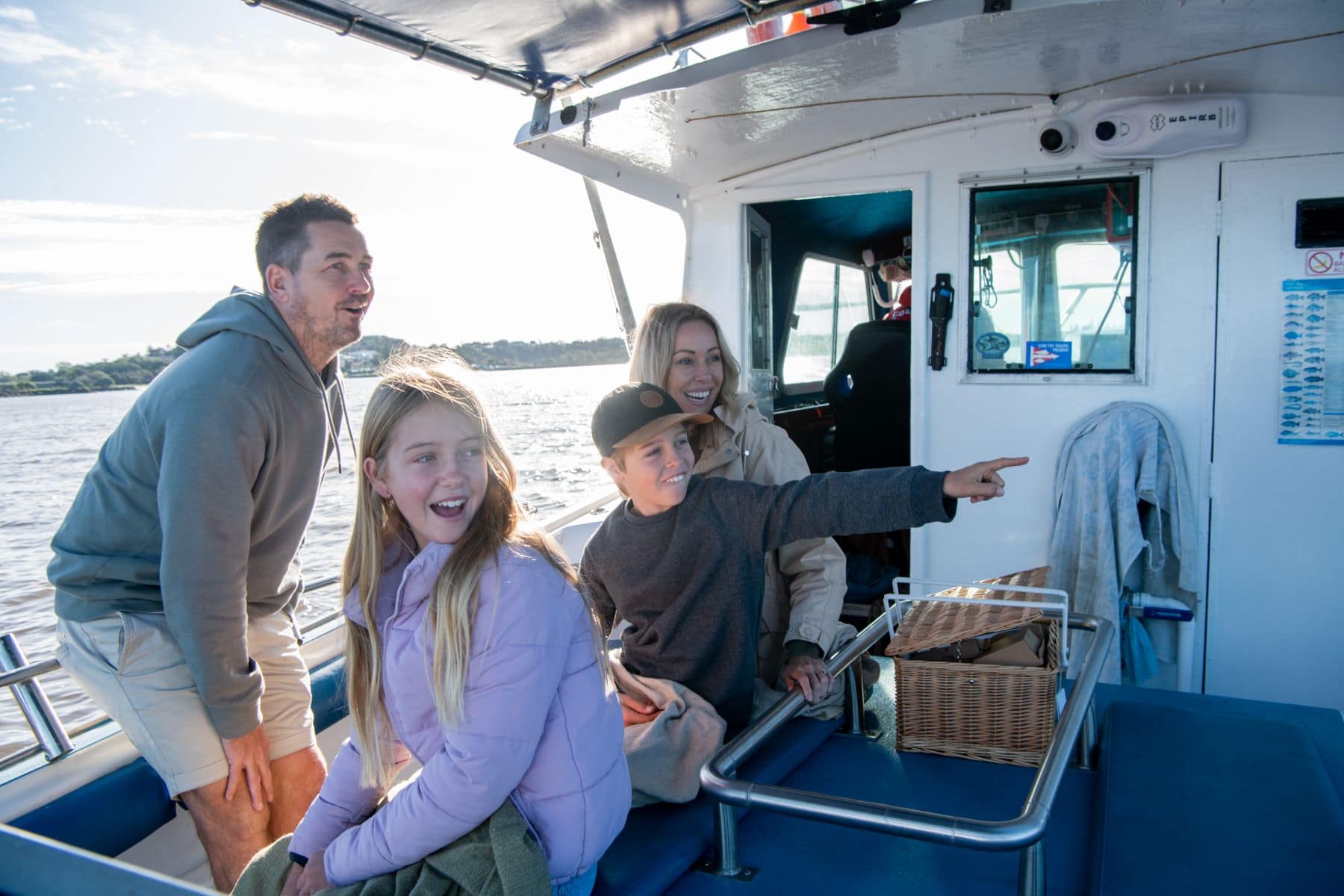Family Fishing Fun with Fozies Fishing Adventures, Ballina A smiling family on board a Fozies Fishing Adventures charter boat in Ballina, enjoying a day out on the Richmond River as a young boy points excitedly.