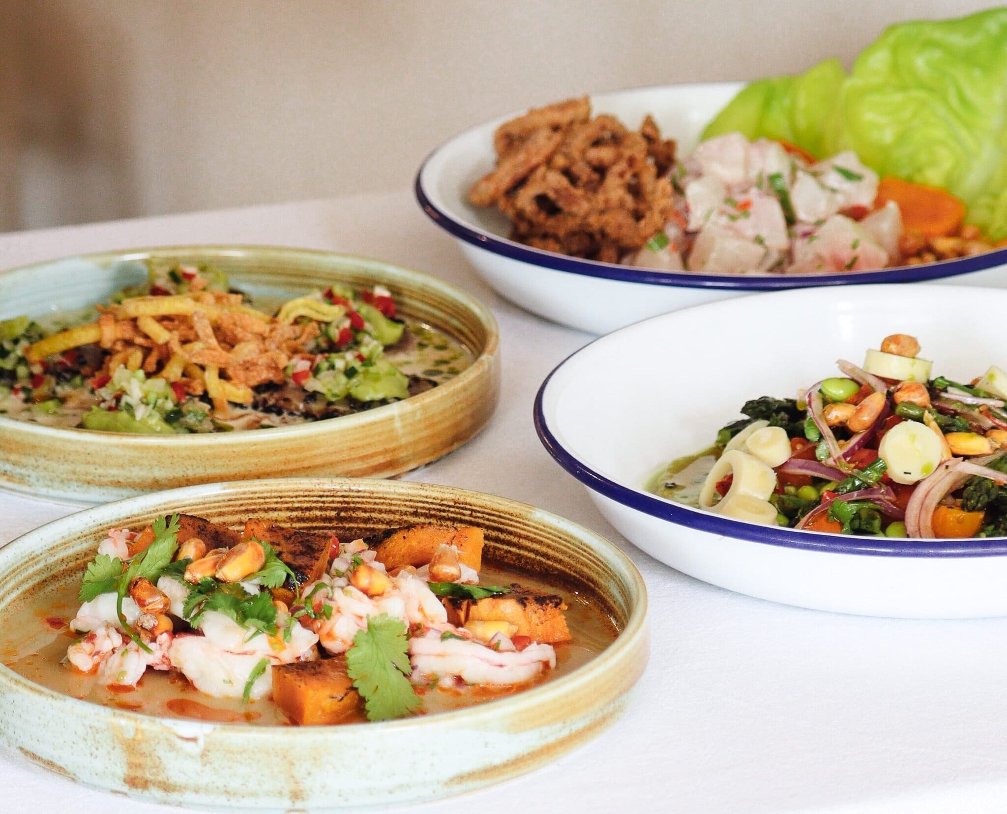 Bonito Peruvian Restaurant – Alstonville A vibrant selection of Peruvian dishes including fresh ceviche, sweet potato, corn, and crisp lettuce cups served on artisan ceramic plates.