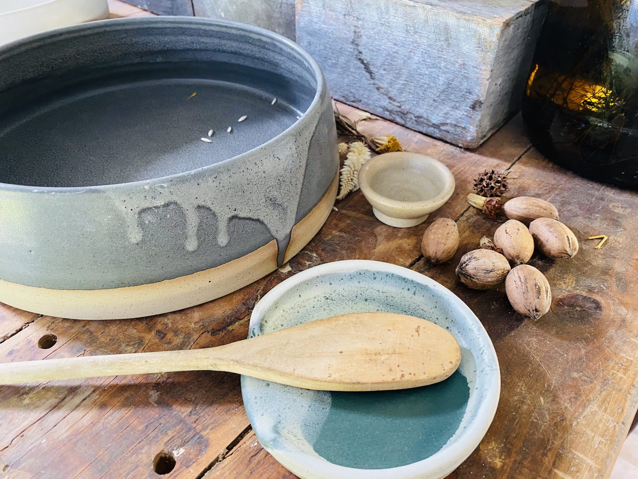 Brooke Clunie Ceramics – Handmade Pottery in the Northern Rivers Handcrafted ceramic mug with green and white glaze made by Brooke Clunie in the Northern Rivers, held over a timber saucer.