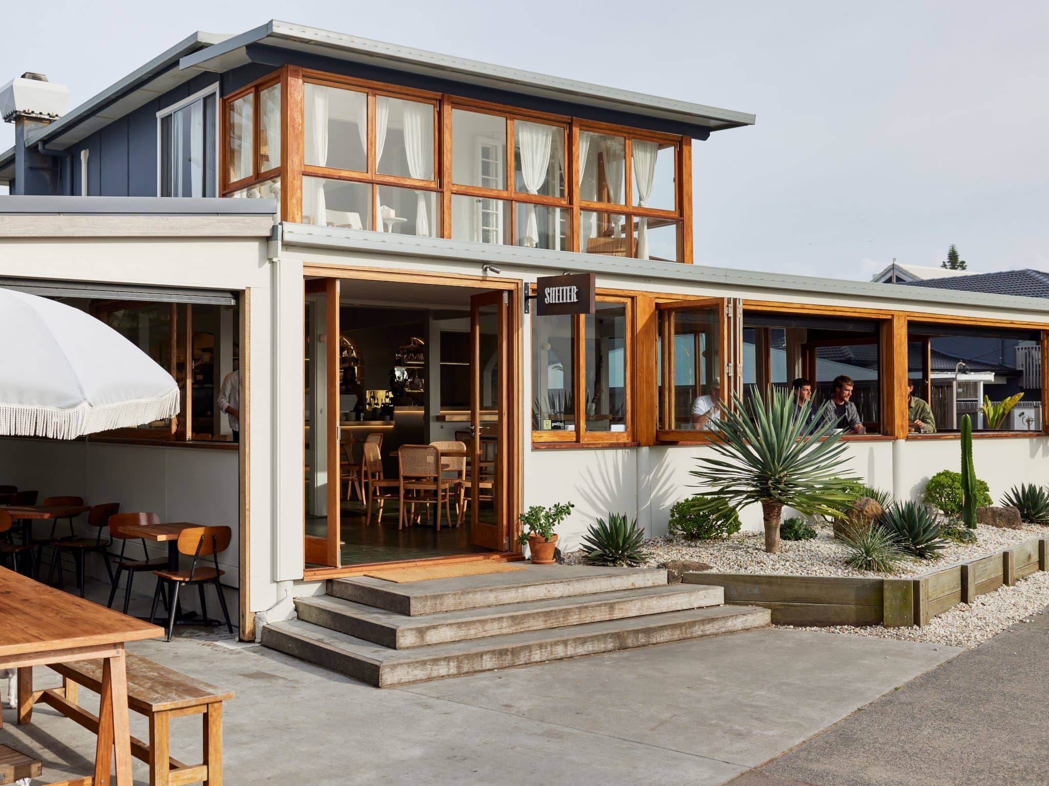 Shelter Restaurant – Beachfront Dining in Lennox Head Exterior of Shelter restaurant in Lennox Head, with modern coastal design, outdoor seating, and desert-style landscaping.