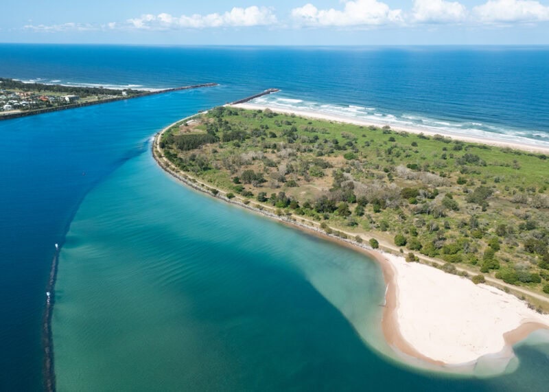 Aerial view of Mobbs Bay in South Ballina, New South Wales, showing the Richmond River mouth, sandy beach, break wall, and coastal vegetation.