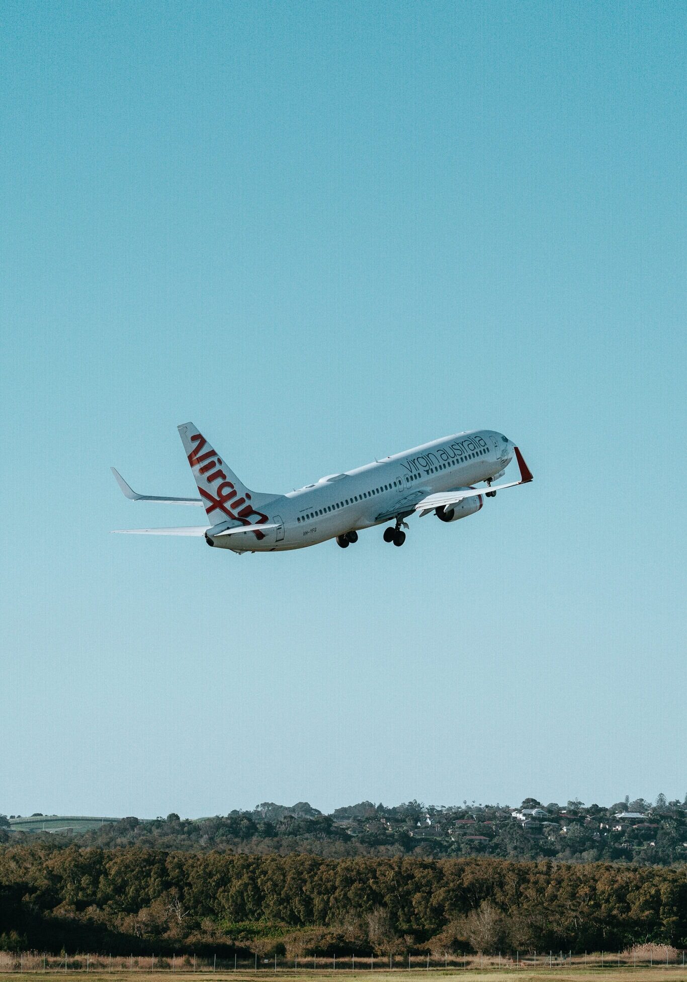 Aircraft taking off from Ballina Byron Gateway Airport with clear blue skies above.