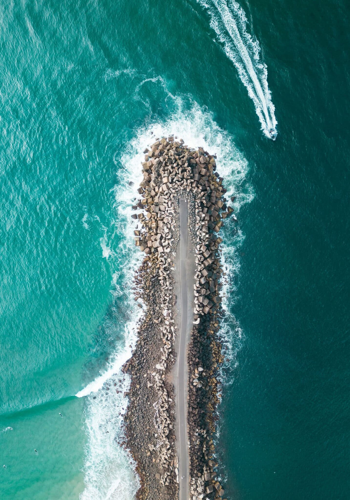 Aerial Perspective of Ballina’s Iconic North Wall Aerial view of North Wall Ballina stretching into the ocean with waves and a speedboat nearby.