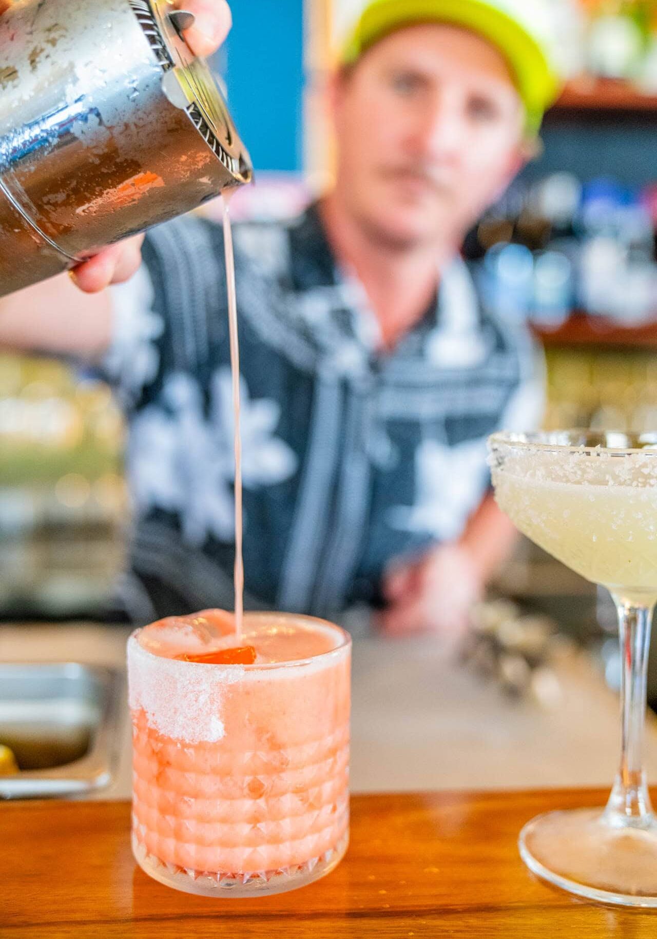 Bartender pouring a pink cocktail into a glass at Kelp bar in Ballina, with a salted rim and fresh garnish.