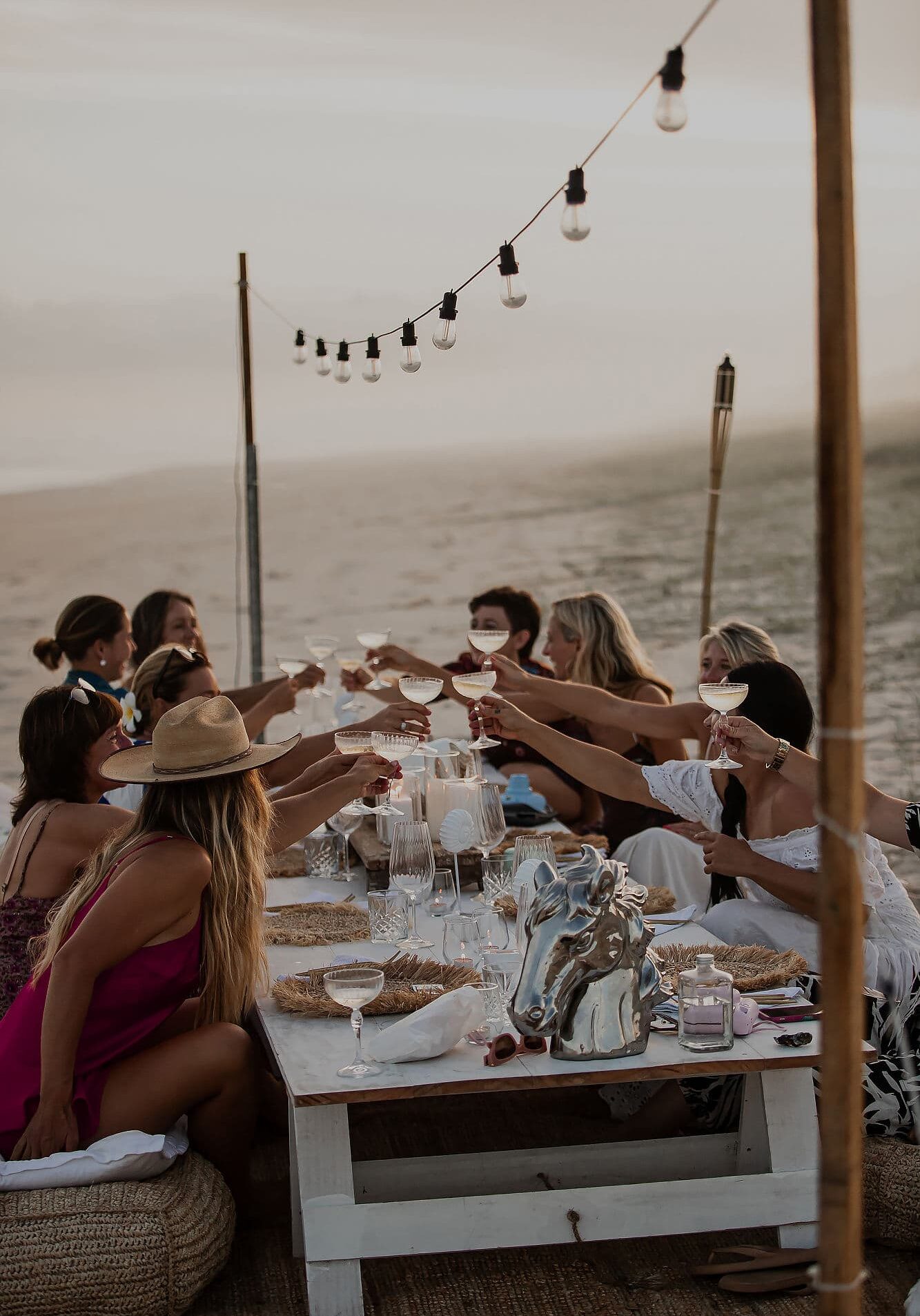 Luxury Beach Retreat Dining – Sugar Beach Ranch, South Ballina NSW Group of women enjoying a sunset toast at an outdoor beachfront table during a Sugar Beach Ranch retreat in South Ballina, New South Wales.