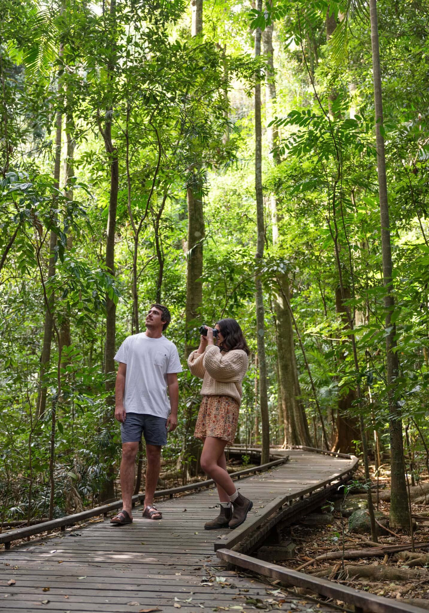 Couple walking along the boardwalk surrounded by lush green trees