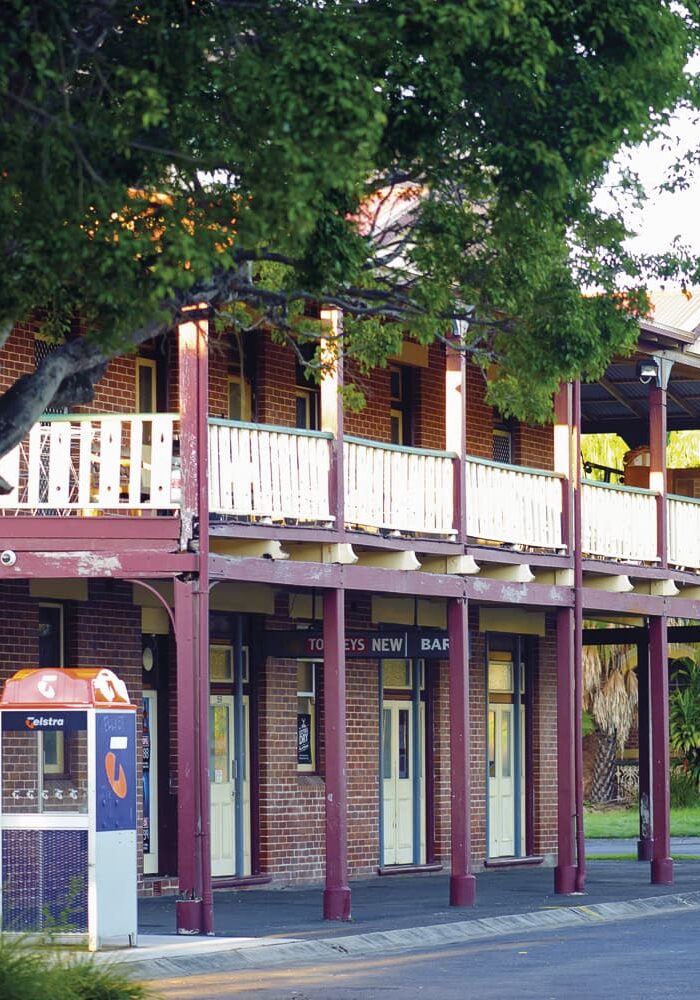 Heritage Pub in the Heart of Wardell Historic two-storey red brick pub with wraparound verandah and vintage Telstra phone box in Wardell, NSW.